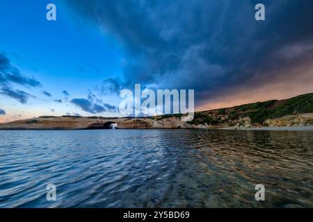 Small eroded pools, temporarily filled with water after a thunderstorm, on the surface of the rocks around the Arco di S'Archittu rock arch. Stock Photo