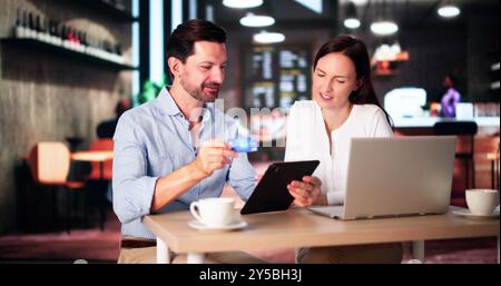 Couple Shopping Online On Laptop In Cafe Stock Photo