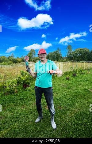 Angle grinder with diamond wheel in hands of smiling man in protective work clothes covered with concrete dust. Stock Photo