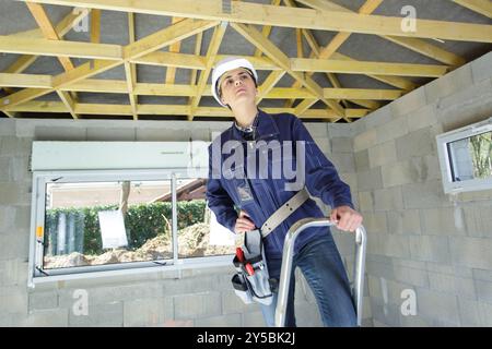 woman as worker wearing protective helmet on stepladder Stock Photo