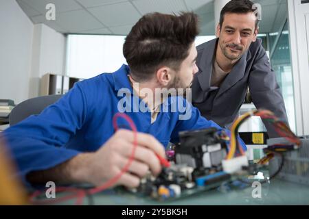 two male masters work in the workshop with electronics Stock Photo