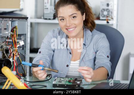 happy female electronic engineer soldering computer motherboard in laboratory Stock Photo
