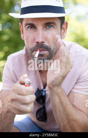 man outdoors poised to light a cigarette Stock Photo