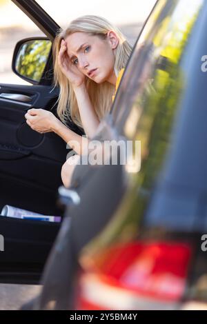 female motorist with head in hands sitting stil Stock Photo