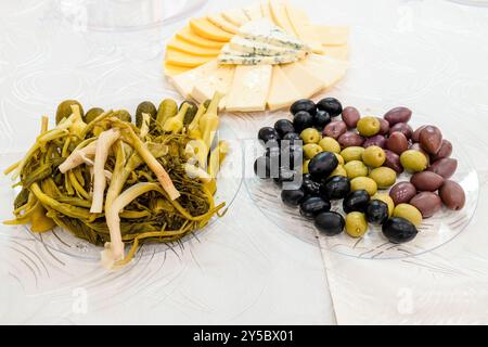 snacks, pickled armenian herbs, vegetables, olives, on plastic plates on table closeup Stock Photo