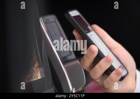 Male hand holding smartphone at POS terminal device Stock Photo