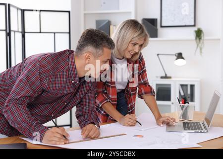 Architects making engineering drawing at wooden table in office Stock Photo