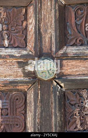 abstract of heavily carved historic church front door made from wood with ornate metal door furniture and large brass door handle. Stock Photo