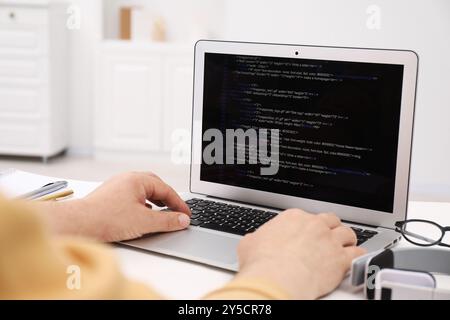 Programmer working with laptop at white desk in office, closeup Stock Photo