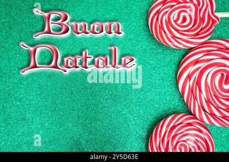 Christmas card with Merry Christmas in Italian. with red and white candy on a green background. Stock Photo