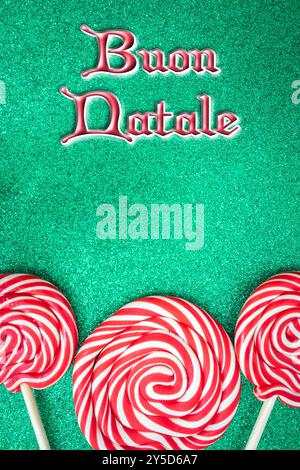 Christmas card with Merry Christmas in Italian. with red and white candy on a green background. Stock Photo