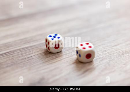 On a rustic wooden table, two dice adorned with vibrant red and blue dots are resting side by side, inviting you to join the fun Stock Photo