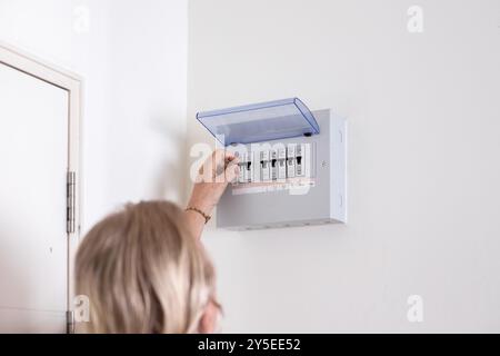 A man turns on a switch on an electrical panel in a room. Distributor Electricity. Stock Photo