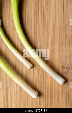 Three green onion scallions on a cutting board Stock Photo