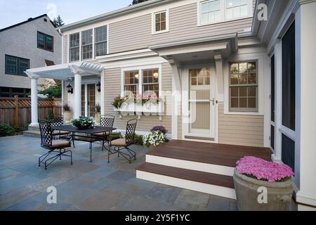 Back exterior of wood house showing back door and screened porch and slate patio from closer angle Stock Photo