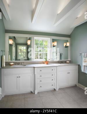 Beautiful bathroom with double sink white vanity with window between two mirrors and white support beams in ceiling Stock Photo