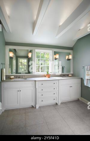 Beautiful bathroom with double sink white vanity with window between two mirrors and white support beams in ceiling Stock Photo