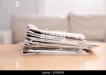 Stack of newspapers in different languages on table indoors Stock Photo