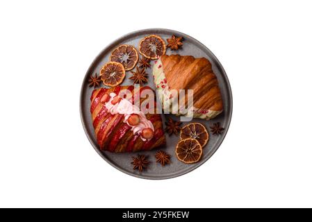 Crispy sweet red croissant with pistachio, raspberry and strawberry on a dark concrete background Stock Photo