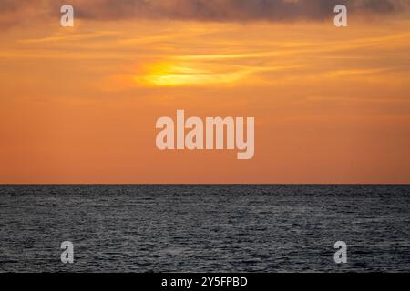 Sunset over the Mediterranean Sea seen from Livorno, Italy, with soft orange hues blending into the horizon. Stock Photo