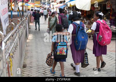 Kolhapur , India - 9 September 2024 Girl in school uniform walking to school with friend hand on her younger brother shoulder at kolhapur Maharashtra Stock Photo