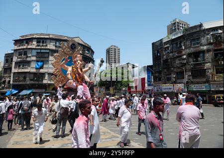 Mumbai, India - 17 September 2024  Carrying a huge idol of Lord Ganesha people are going for immersion with the band playing and singing and throwing Stock Photo