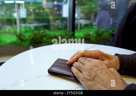 Hands of an elderly male cafe customer at a table waiting Stock Photo