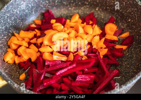Shot of the freshly cut beetroots, onions and carrots stewed on the frying pan Stock Photo