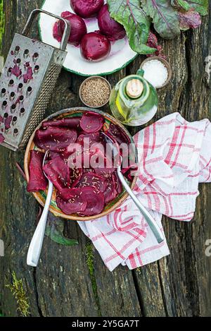 Bowl of Fresh Beetroot salad with oil and cumin seeds on wooden table in the garden Stock Photo