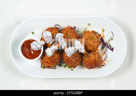 white plate with tasty chicken lollipops and sauce on white background. top view Stock Photo