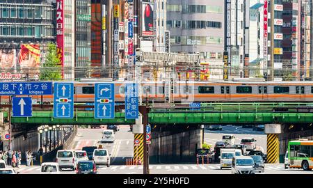 Famous Shinjuku viewpoint. Railway bridge over Ome-Kaido Avenue with a compressed perspective view of the Yunika Building and others. Train on bridge. Stock Photo