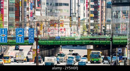 Famous Shinjuku viewpoint. Railway bridge over Ome-Kaido Avenue with a compressed perspective view of the Yunika Building and others. Traffic and sign Stock Photo