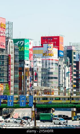 Famous Shinjuku viewpoint. Railway bridge over Ome-Kaido Avenue with a compressed perspective view of the Yunika Building and others. Train on bridge. Stock Photo