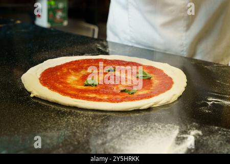 A chef preparing a pizza with tomato sauce Stock Photo