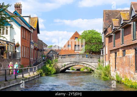 Two people walking towards Winchester City Mill A restored 18th-century watermill by the River Itchen in Winchester Hampshire England UK GB Europe Stock Photo