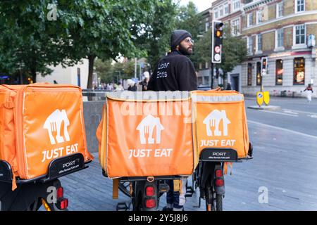 One uber eats driver and three orange JUST EAT food delivery warmer and container in the back of three bikes in London England UK Stock Photo
