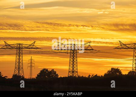 Power pylons of an overhead line at sunset Stock Photo