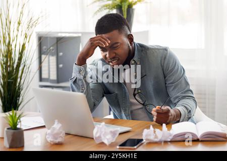 Annoyed black employee looking at laptop screen with despair Stock Photo
