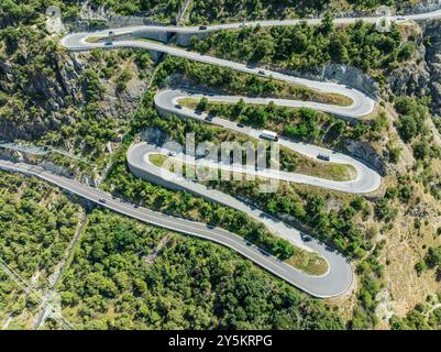 Mountain pass road with multiple hairpins, water pipeline, aerial view, drone shot.  Valais, Switzerland Stock Photo