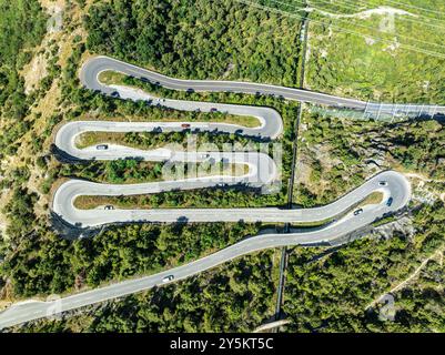 Mountain pass road with multiple hairpins, water pipeline, aerial view, drone shot.  Valais, Switzerland Stock Photo