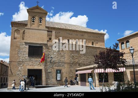 Historic church in Toledo with flag, people strolling and beautiful blue sky and trees in the background, El Transito Synagogue, Transito, Toledo, Ca Stock Photo