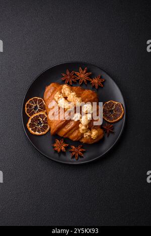 Sweet crispy croissant with salted caramel and glazed popcorn on a dark textured background Stock Photo