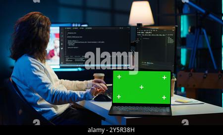 Admin using green screen laptop to implement security measures, protecting company systems and data. IT worker testing and debugging code for software applications on chroma key notebook, camera A Stock Photo
