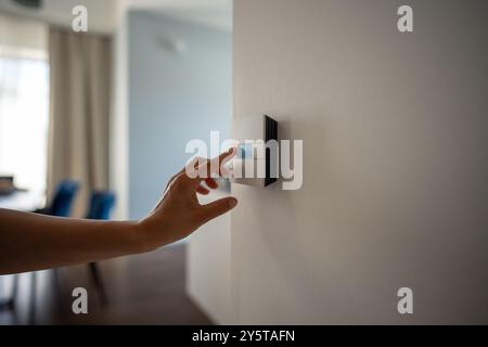 Woman hand adjusts underfloor heating settings in smart home panel for comfort in cold season Stock Photo