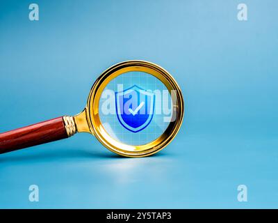 Cybersecurity, digital data and information online protection technology concept. Shield padlock icon in golden magnifying glass lens, isolated on net Stock Photo