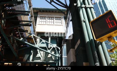 New York elevated subway, metropolitan bridge, metro track above street. Railway transport over road. Railroad line. Queens public transportation. Long Island city, United States. Yellow traffic light Stock Photo