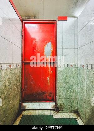 Mysterious Red Door. The toilet door is worn and looks dirty. Stock Photo