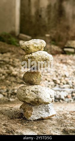 Stacked stone cairn pyramid standing on grassy hill slope beside green ...