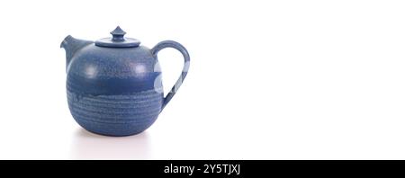 A blue ceramic teapot with a round body and smooth finish stands prominently against a white background, showcasing its elegant design and craftsmansh Stock Photo