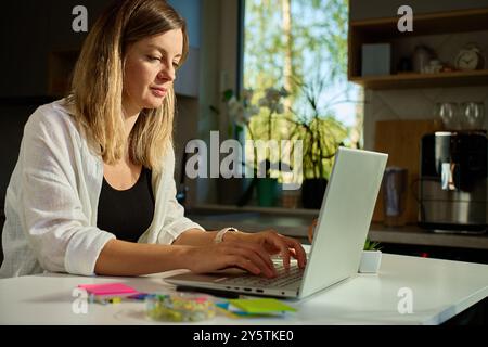 Focused woman working on laptop at home, hands typing on keyboard. Concept of freelance and remote work Stock Photo
